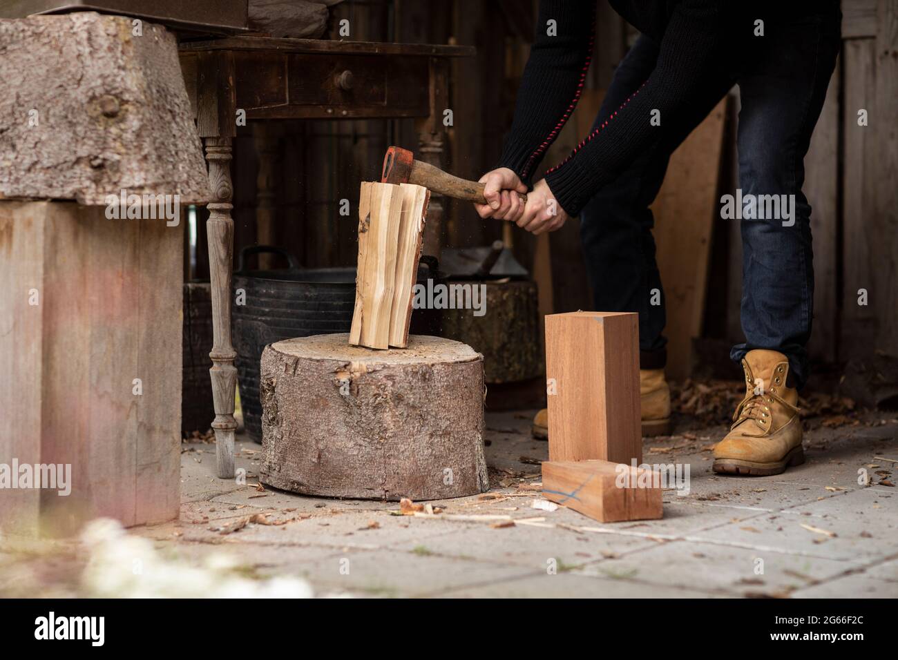 A lumberjack splitting logs of wood with old axe a big wooden stump to