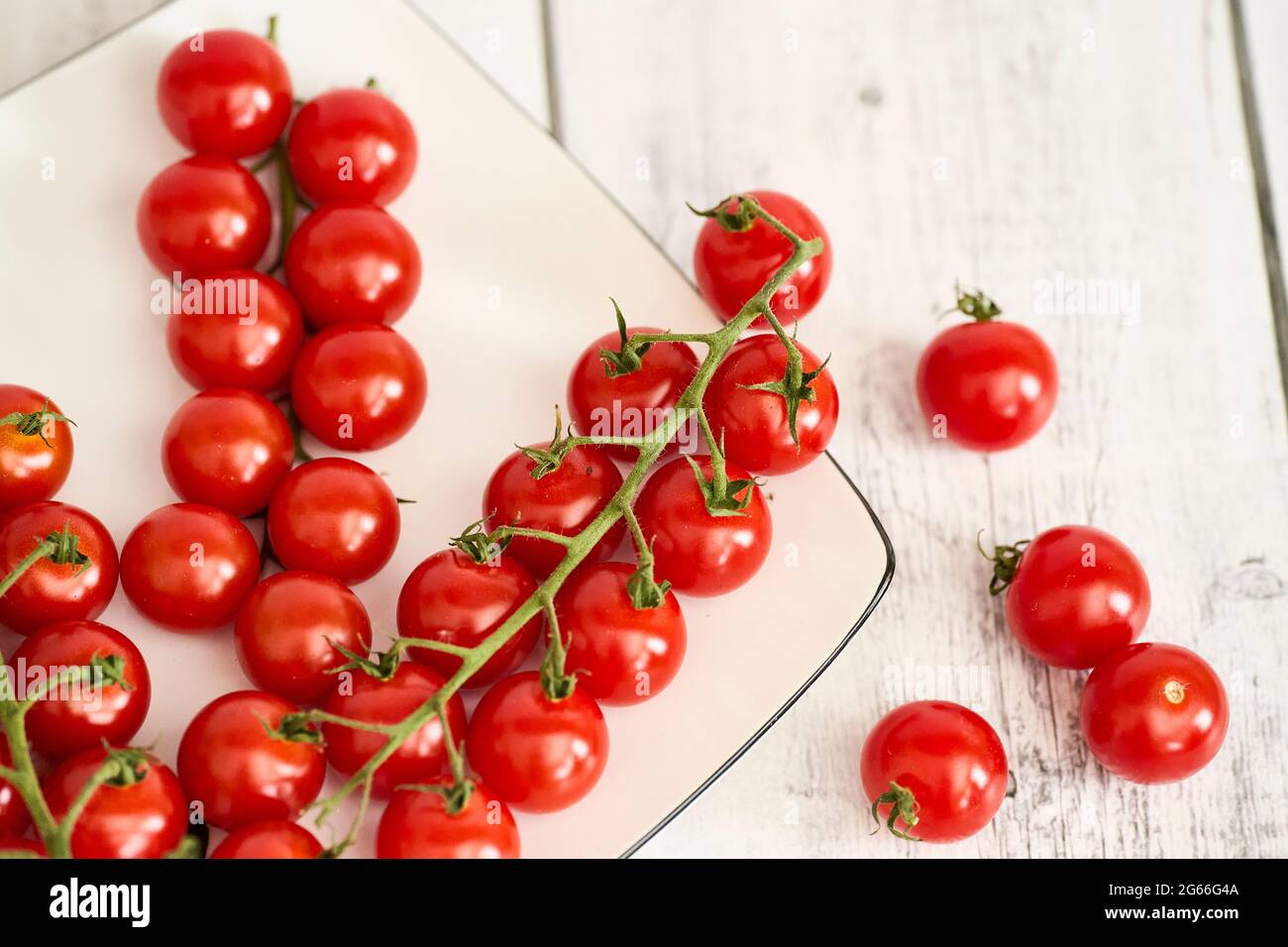 Red Cherry Tomatoes On A White Plate And White Wooden Table. Fehraltorf, Switzerland Stock Photo