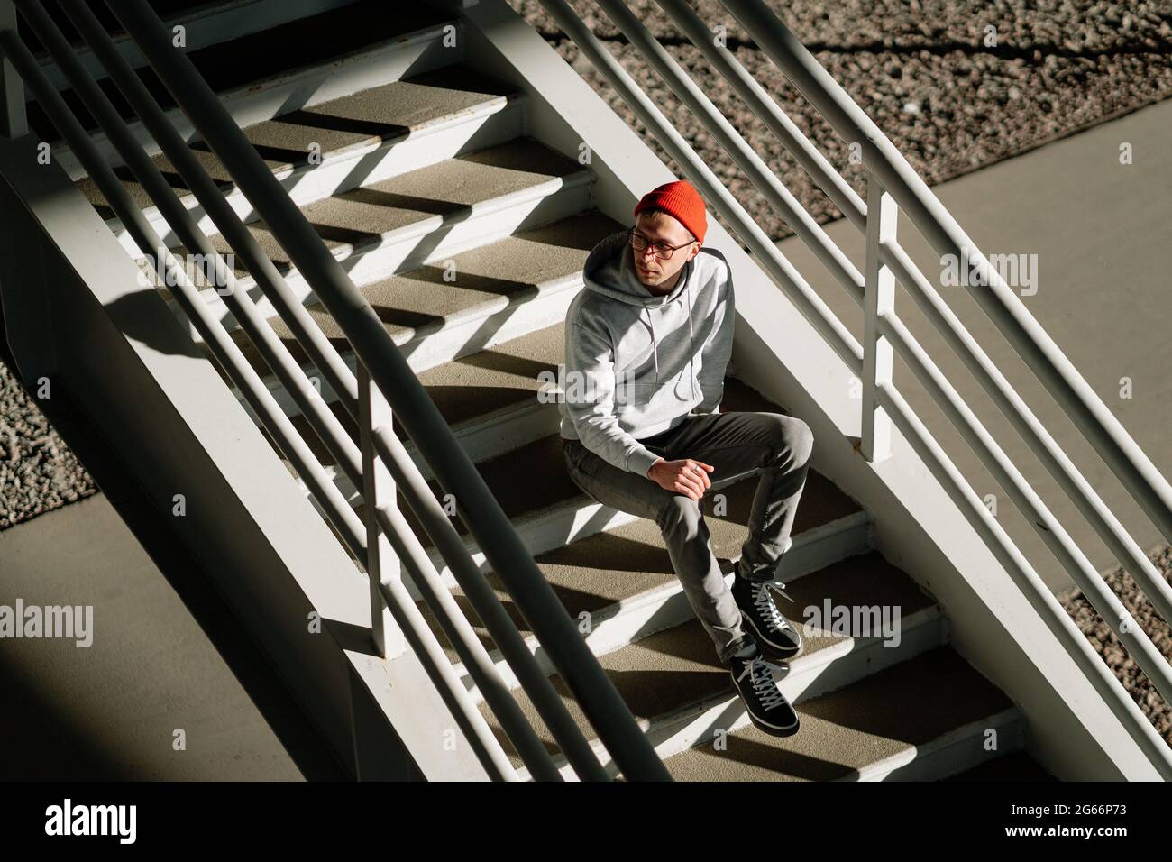 Male hipster alone on stairs in urban city building wear trendy glasses and street fashion clothes Stock Photo