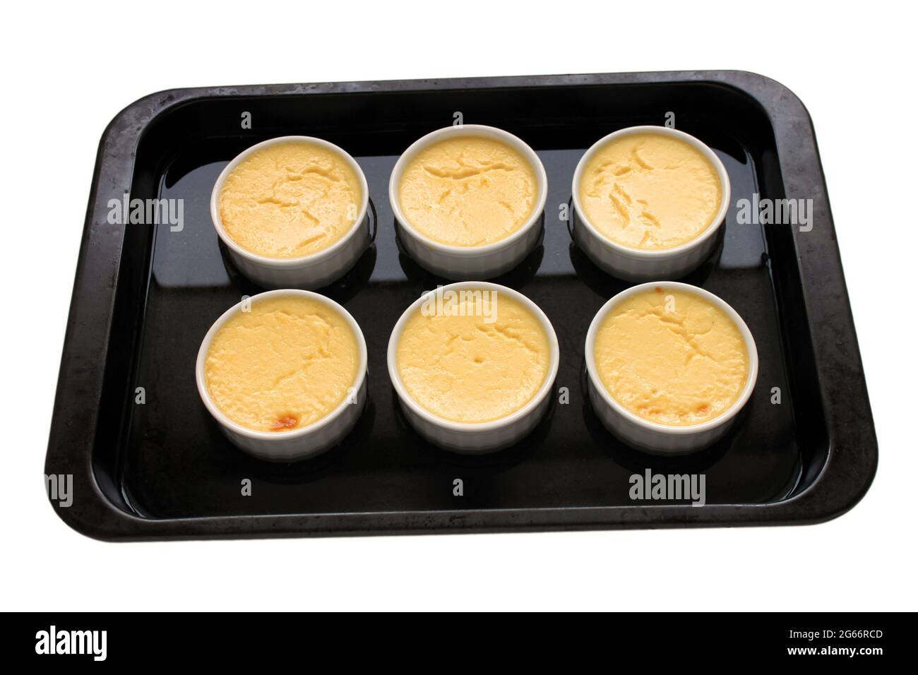 Cooked creme caramel in an isolated bain marie. Stock Photo