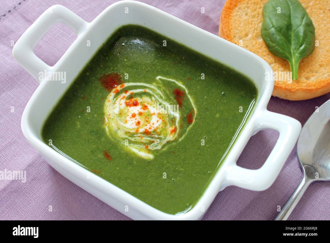 A freshly made bowl of curried spinach and coconut soup on a linen placemat. Stock Photo