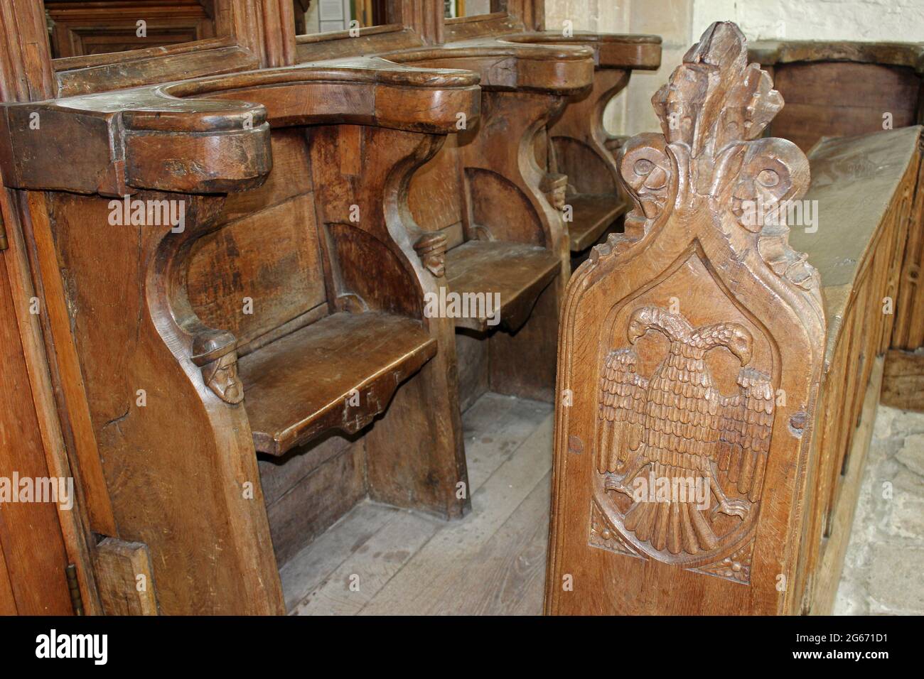 Double Headed Eagle and Carved Wooden Heads On Choir Stall dating to 16th Century at St Beunos, Clynnog Fawr, Wales Stock Photo