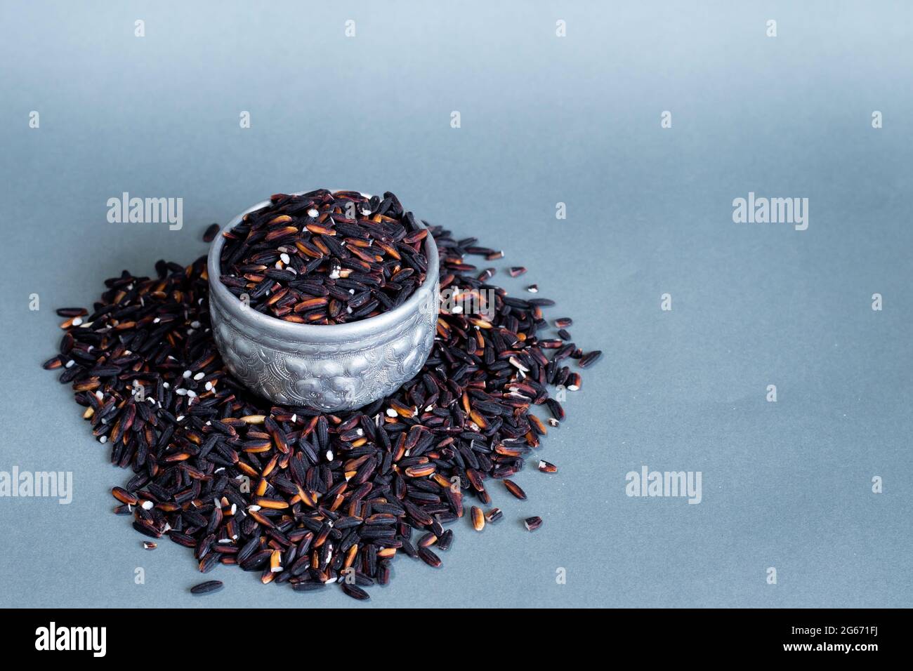Black rice in a silver container on a gray background. Copy space. Stock Photo
