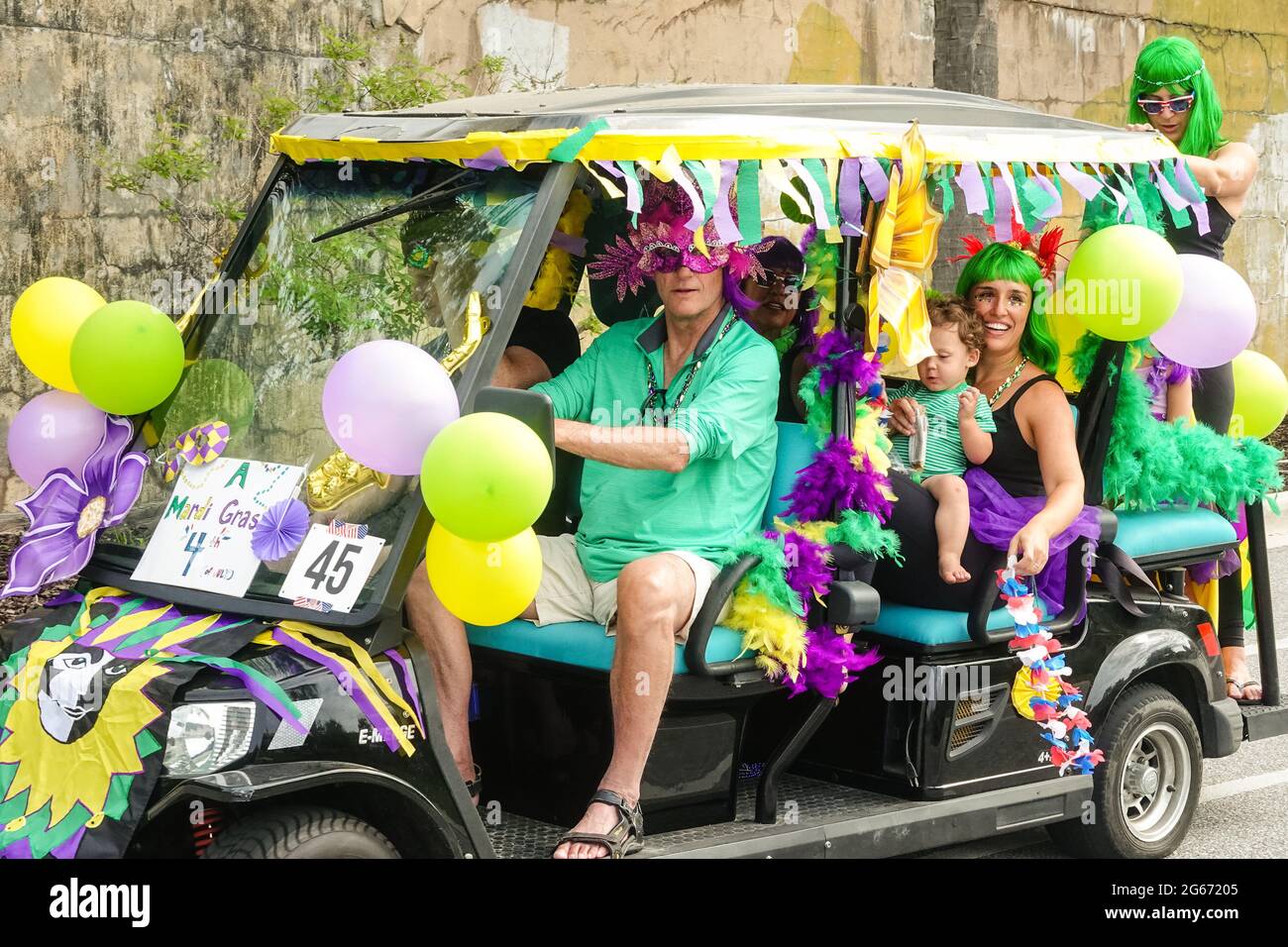 Sullivans Island, South Carolina, USA. 3rd July, 2021. A family drives their golf cart decorated in a Mardi Gras theme during the annual Bicycle and Golf cart parade celebrating Independence Day July 3, 2021 in Sullivans Island, South Carolina. Credit: Planetpix/Alamy Live News Stock Photo