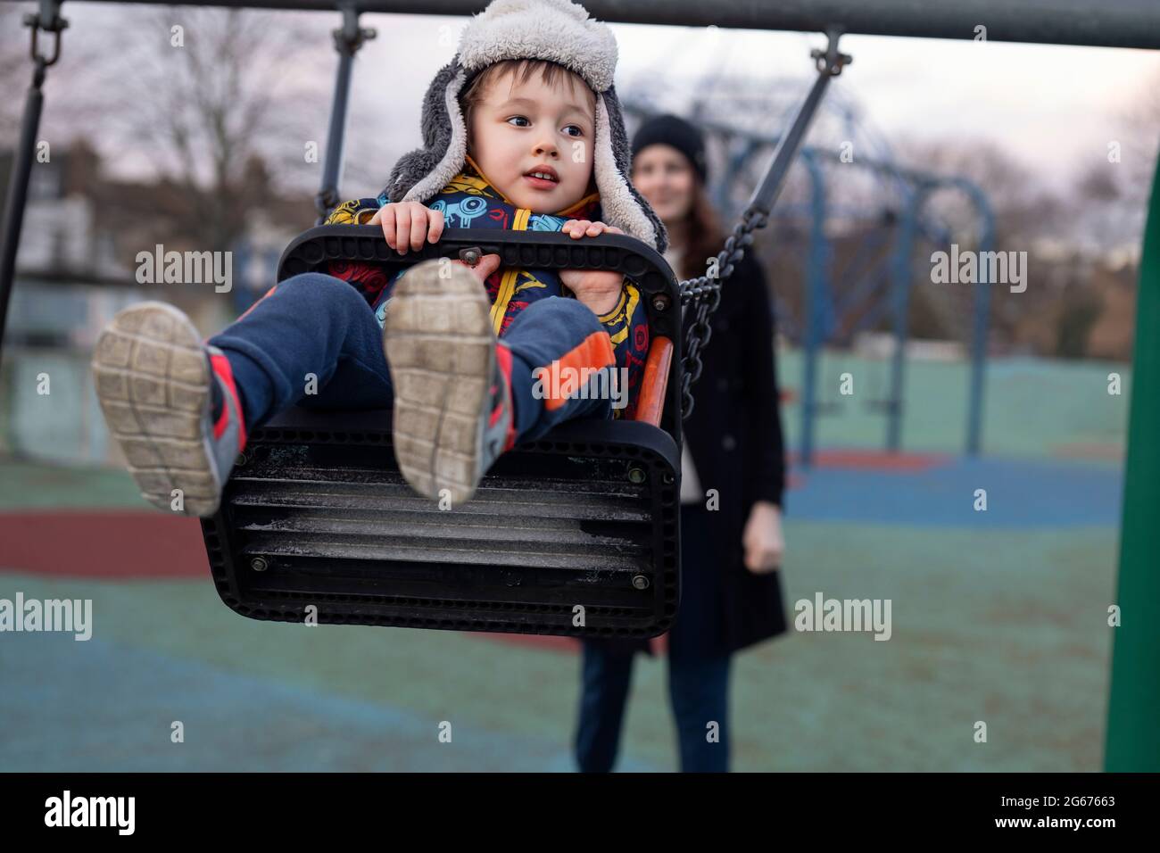 A young child being pushed on a swing Stock Photo