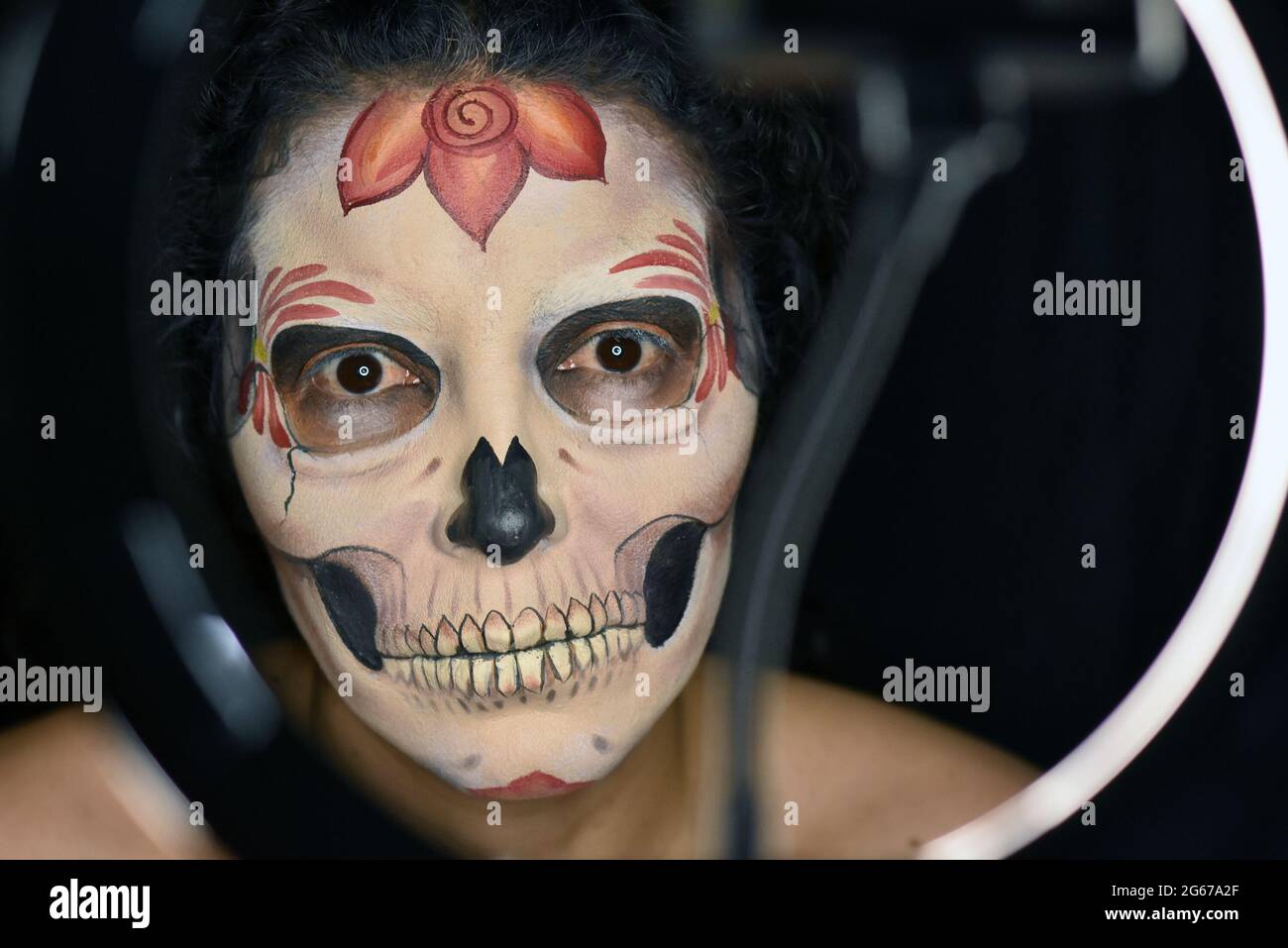 A makeup artist poses as she begins her transformation into Catrina, a traditional Day of the Dead figure. Stock Photo
