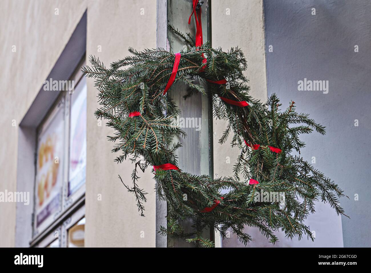 Christmas fir branch wreath with red ribbon hanging on wall Stock Photo ...