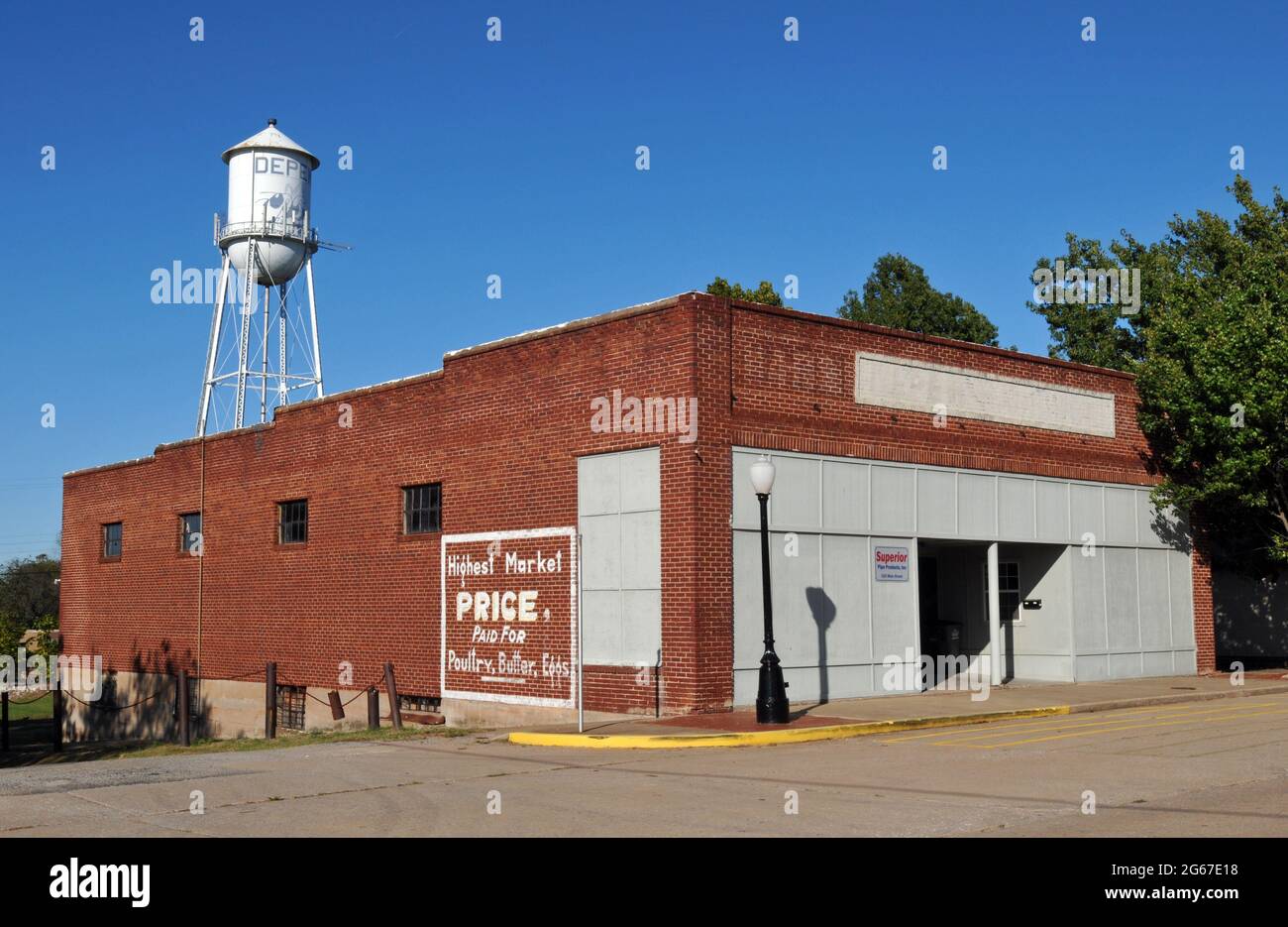 An old-fashioned water tower rises above a brick commercial building on Main Street in the Route 66 town of Depew, Oklahoma. Stock Photo