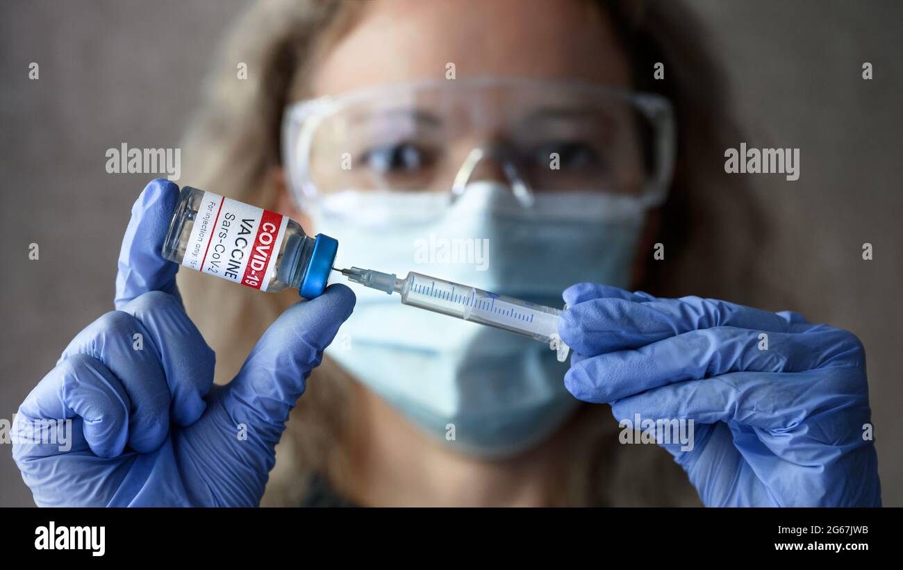 Coronavirus vaccine in doctor hands, nurse holds syringe and COVID-19 vaccine vial. Bottle with vaccine for injection, selective focus. Concept of cor Stock Photo