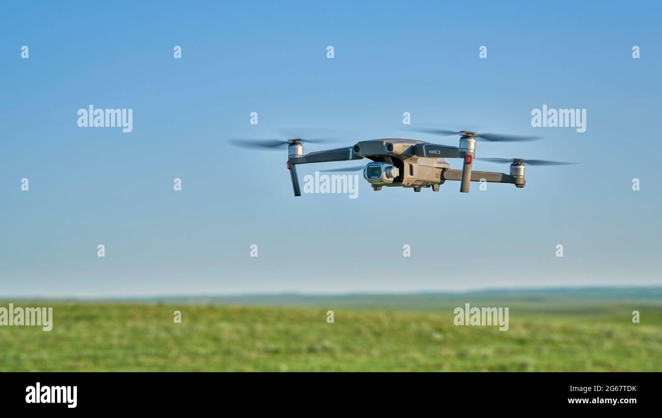 New Raymer, CO, USA - June 8, 2021:  Radio controlled DJI Mavic 2 Pro quadcopter drone is flying over green prairie. Stock Photo