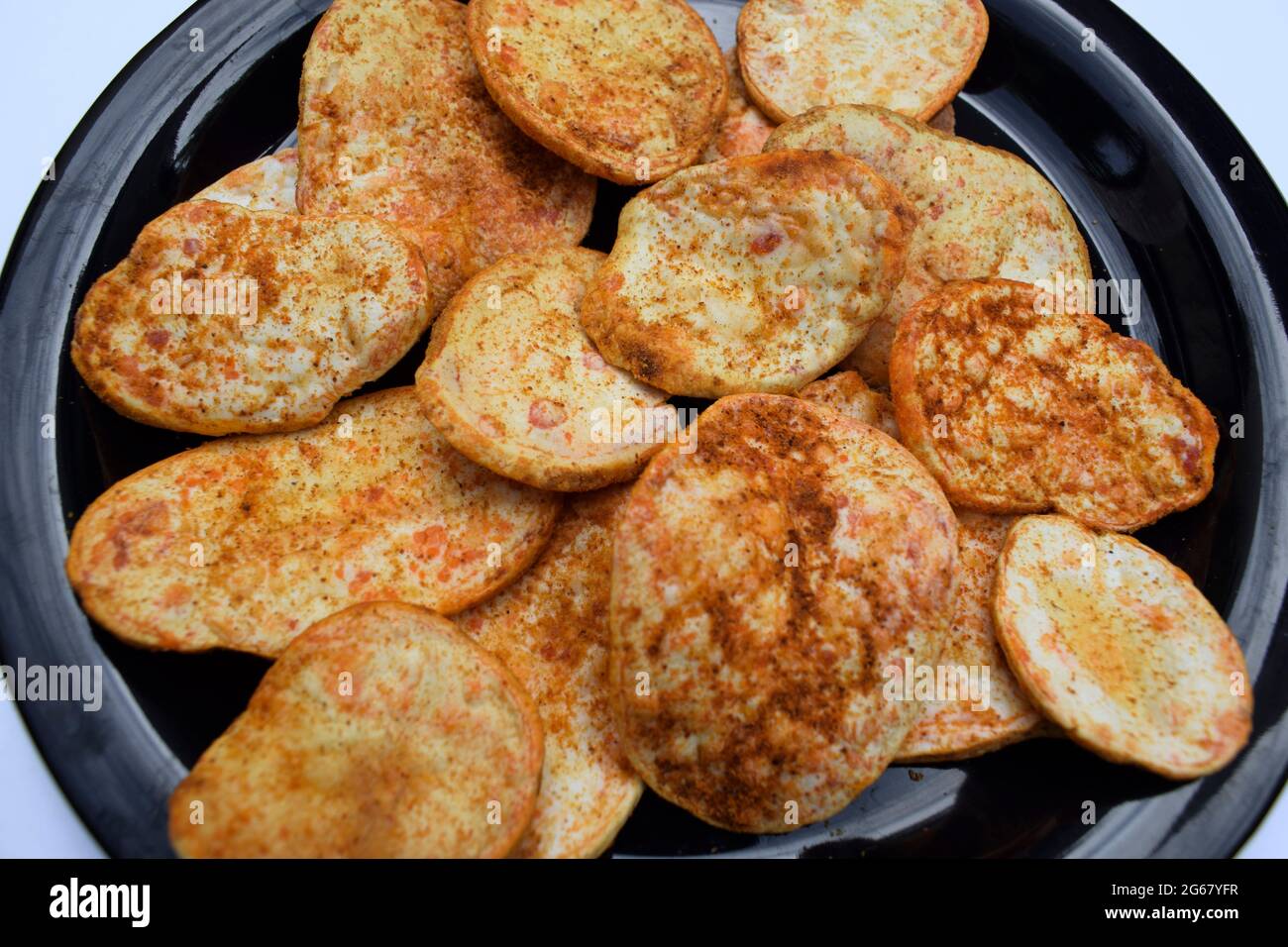 Tasty and crispy thick sundried potato chips wafers. Red chilly sprinkled spicy sun dried without frying munching tea time indian snack item Stock Photo