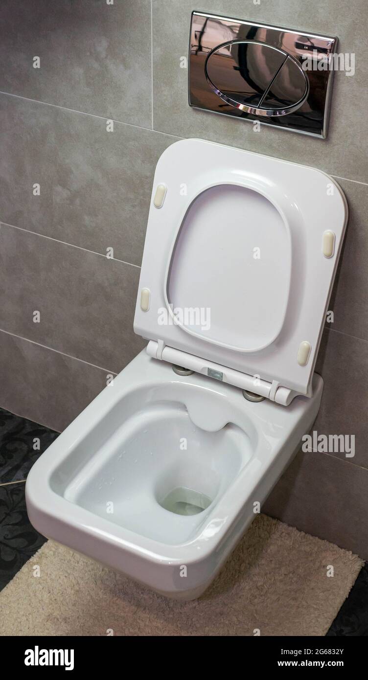 White toilet bowl in the interior, modern toilet. Disinfection of the toilet, cleaning the toilet, washing away dirt from the toilet, flushing away Stock Photo