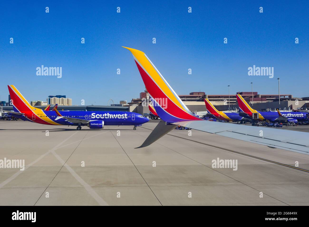 A formation of Southwest Airlines planes at terminal gates at Las Vegas McCarran International Airport in Las Vegas, NV, with casinos in the distance Stock Photo