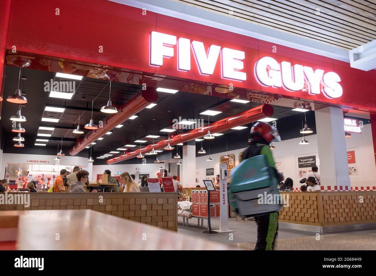 Deliveroo guy leaving Five guys restaurant where people eat in at