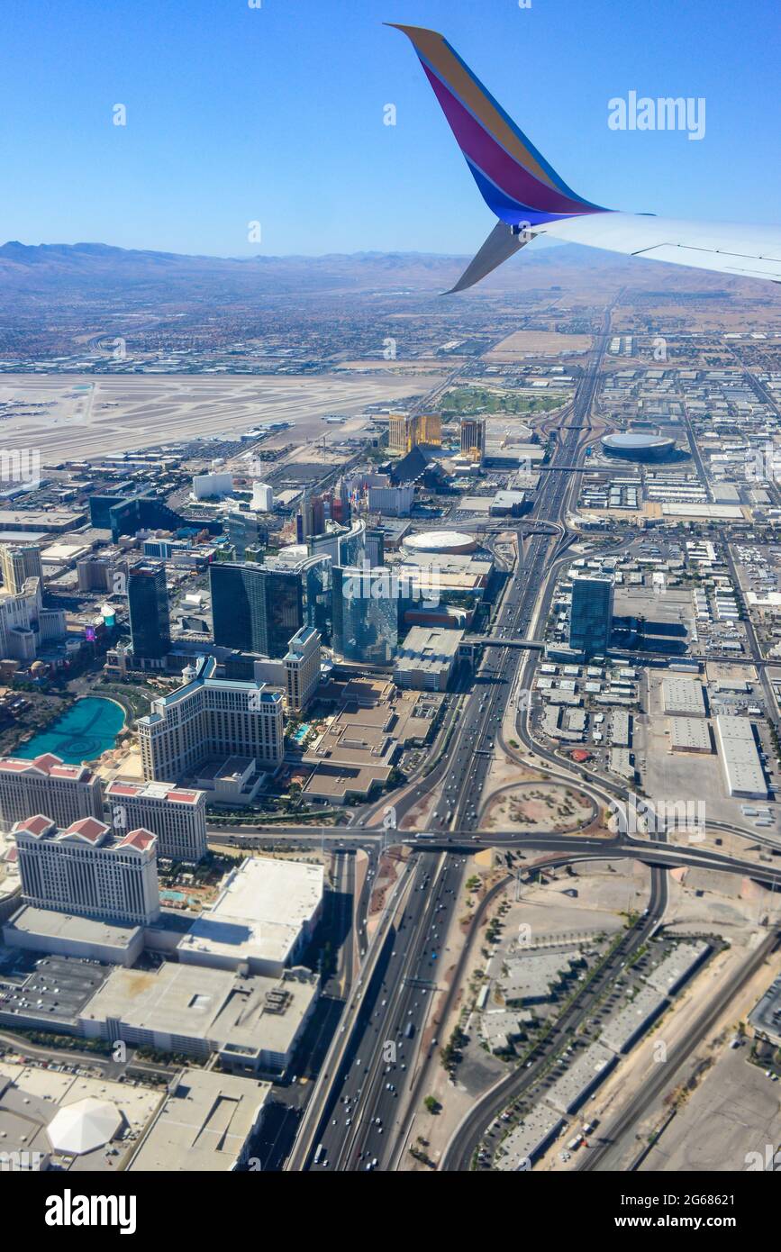 A jet wing tip of an 780 Max airplane in the foreground of an aerial view of Interstate 15 and the  Vegas strip area soon after liftoff from Las Vegas Stock Photo