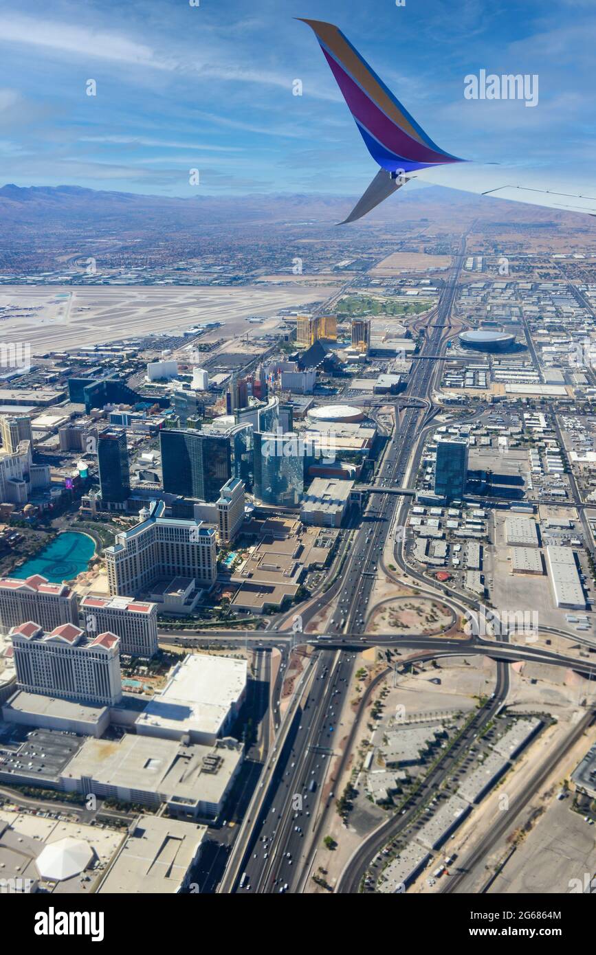 A jet wing tip of an 780 Max airplane in the foreground of an aerial view of Interstate 15 and the  Vegas strip area soon after liftoff from Las Vegas Stock Photo