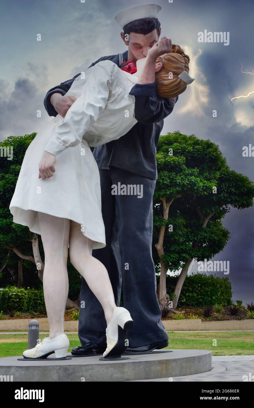 A woman celebrating her American citizenship in front of the statue, 'Embracing Peace', of a sailor kissing a nurse at Tuna Harbor Park, San Diego, CA Stock Photo
