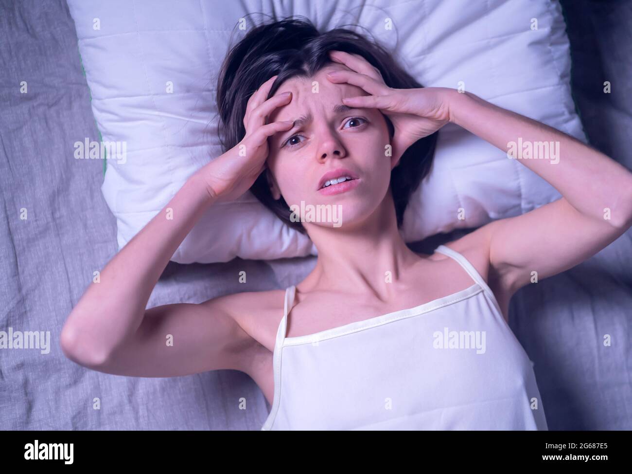 A tired woman has trouble sleeping, insomnia and headaches. Stock Photo