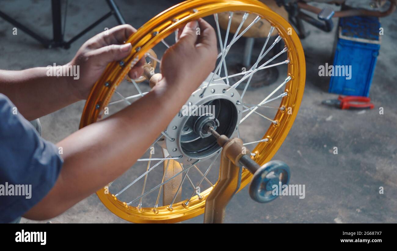 Technician man working motorcycle wheel has spokes weave up on mechanic