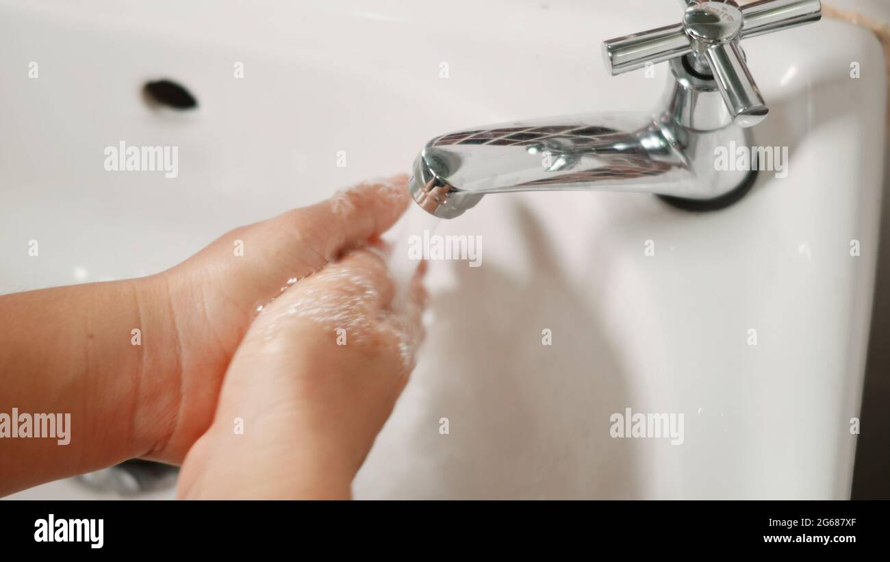 Closeup young woman hands using soap and washing hands under the water ...