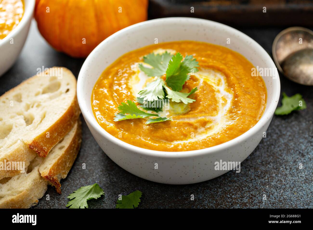 Pumpkin soup served with cream and cilantro Stock Photo