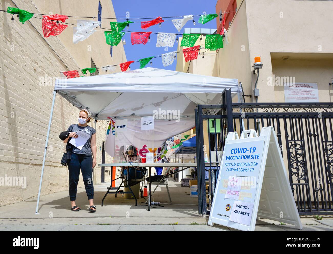 Covid-19 Vaccination site on the sidewalk set up with tent and workers offering Pfizer vaccines with paper flags decoration in Little Italy, San Diego Stock Photo