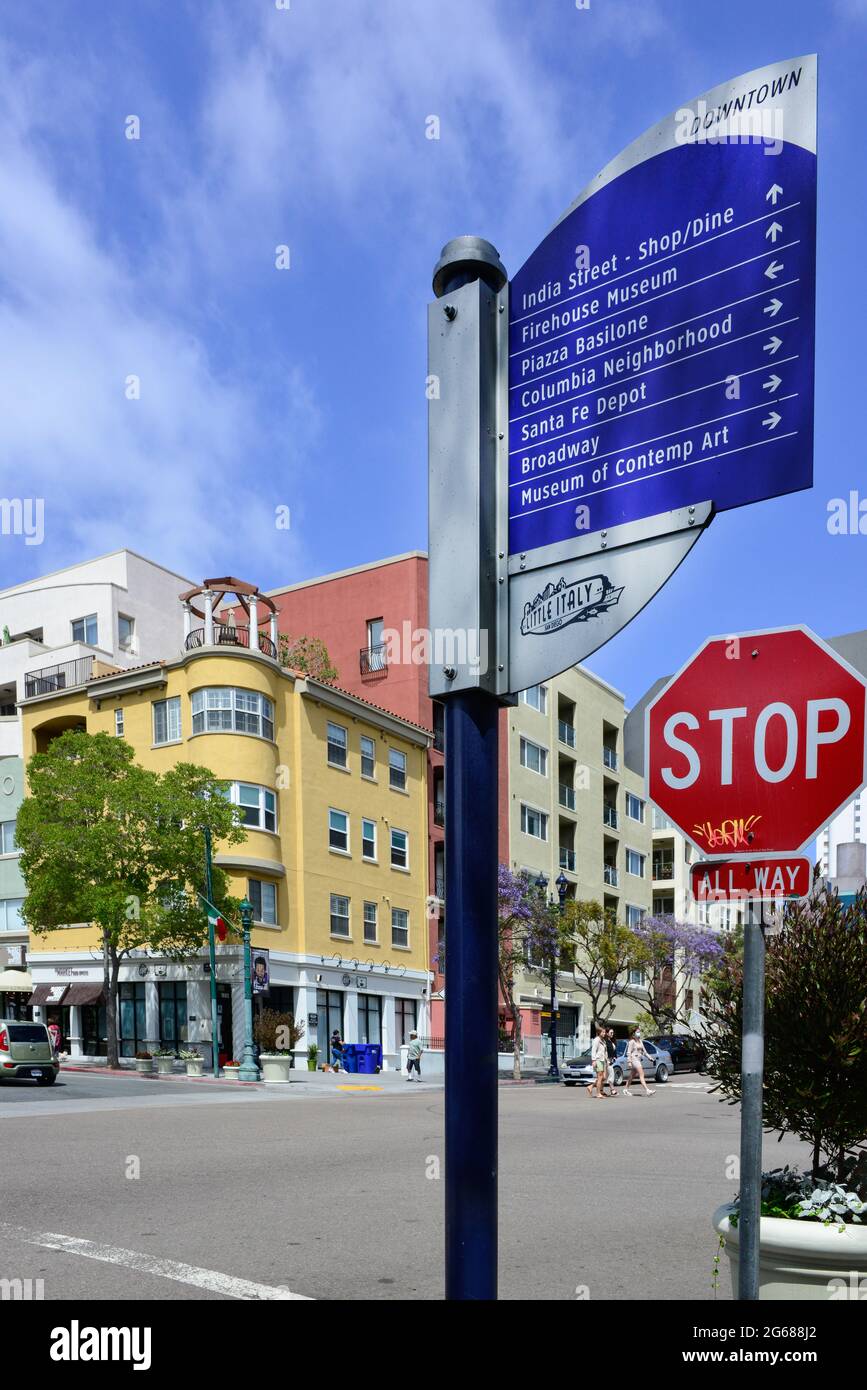 Close up of street sign for neighborhood attractions in Little Italy, with people walking and colorful buildings in downtown San Diego, CA Stock Photo