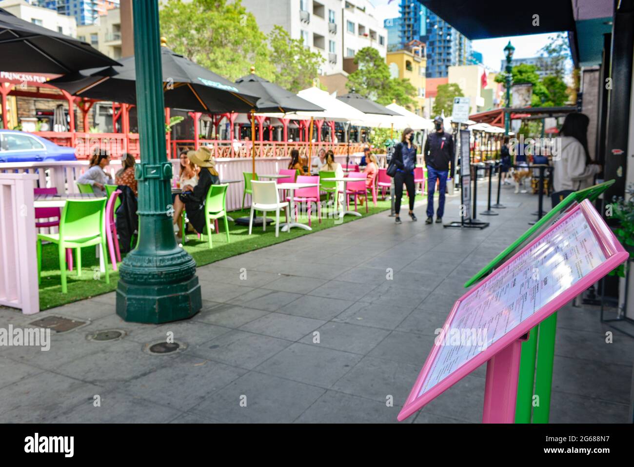 Menu boards in foreground of street scene, with people strolling by