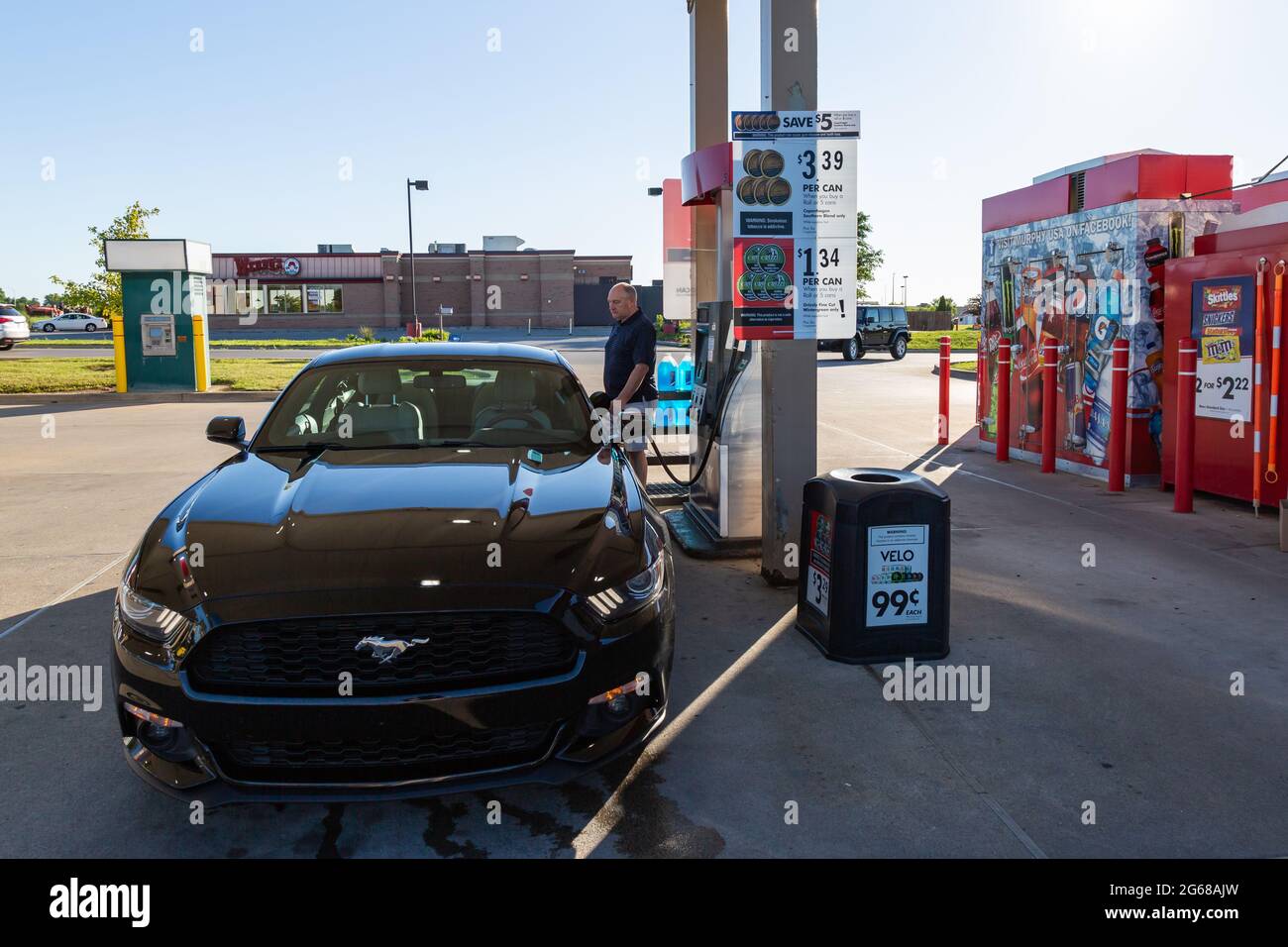 A man pumps gasoline into a black 2015 Ford Mustang at a Murphy USA gas station in Fort Wayne, Indiana, USA. Stock Photo