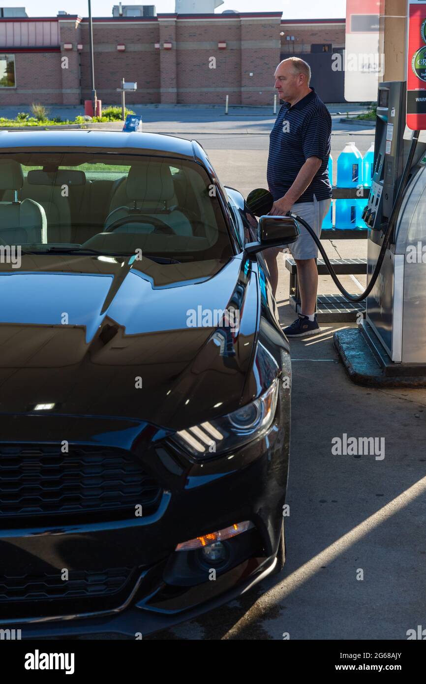 A man pumps gasoline into a black 2015 Ford Mustang at a Murphy USA gas station in Fort Wayne, Indiana, USA. Stock Photo