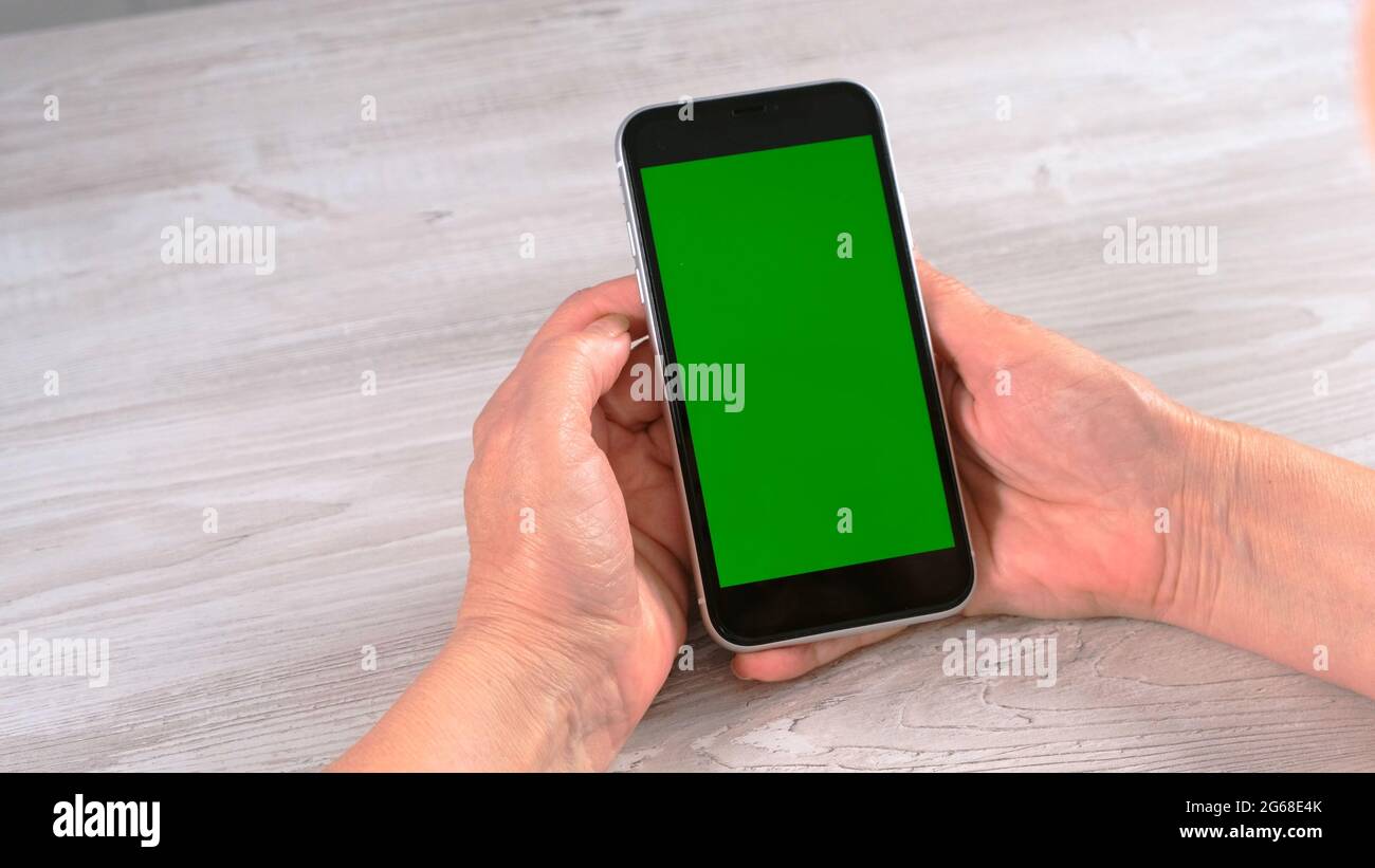 Middle-aged female senora uses an iPhone smartphone with a chroma key screen, copy space. Online shopping concept, use of mobile applications: Moscow Stock Photo
