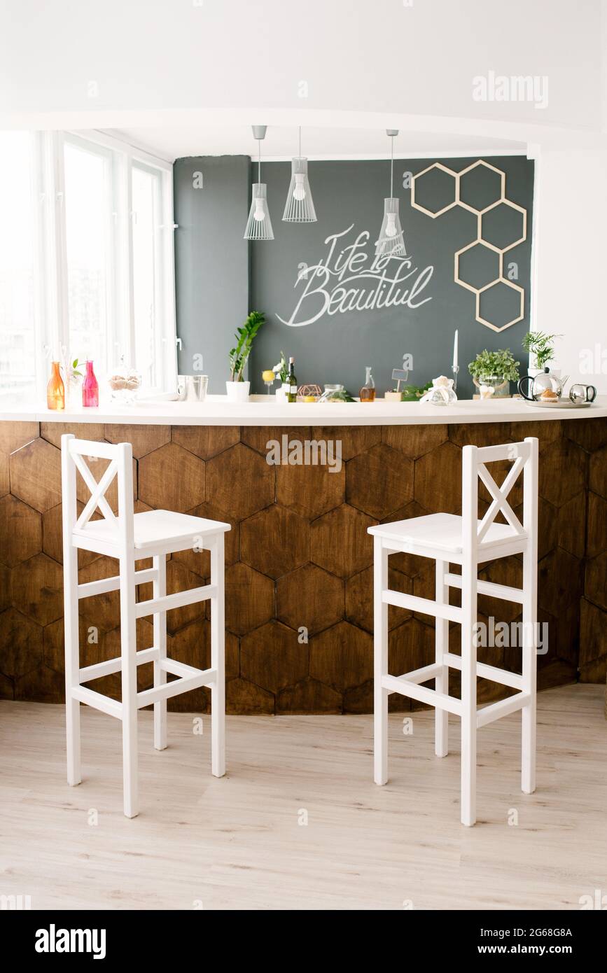 A Stylish Modern Bar Counter Decorated With Wooden Tiles And Two White Bar  Stools In The Living Room Of The House. Scandinavian Interior Design Stock  Photo - Alamy