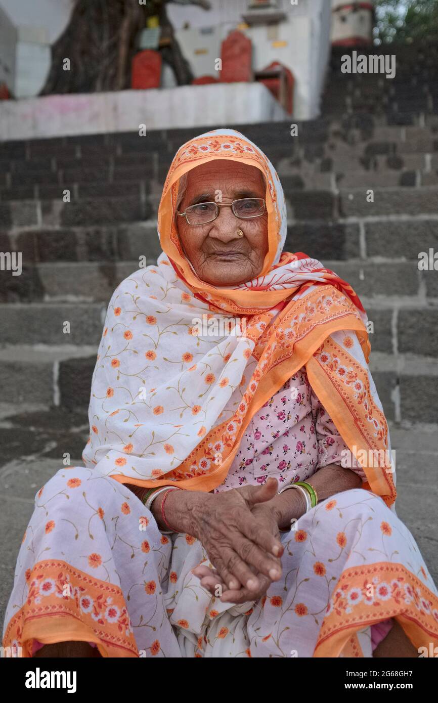An elderly Hindu widow sitting by sacred Banganga Tank, a Hindu pilgrimage site in Walkeshwar, Mumbai (Bombay), India Stock Photo