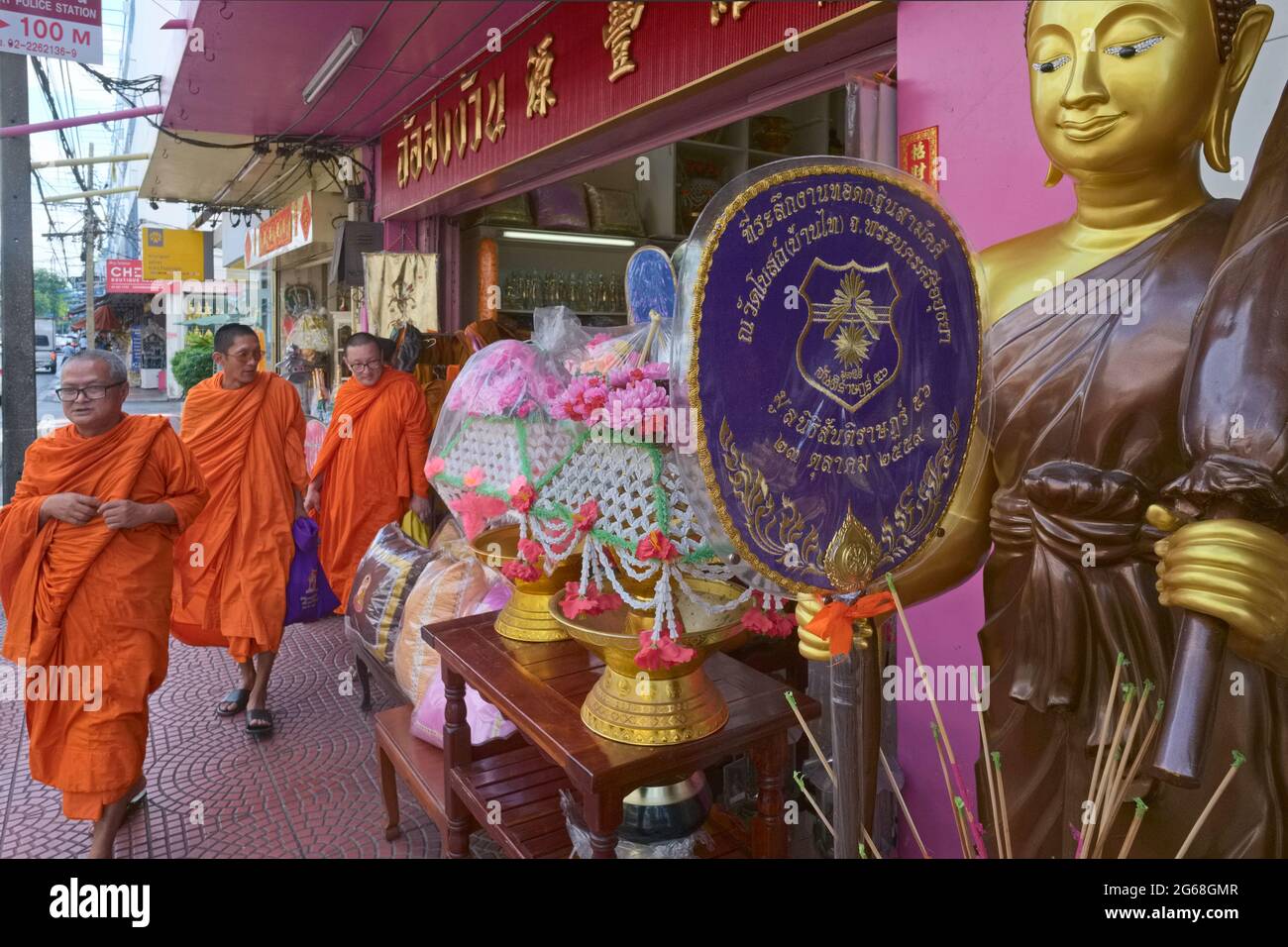 Three Buddhist monks in front of a shop selling Buddhist ritual objects