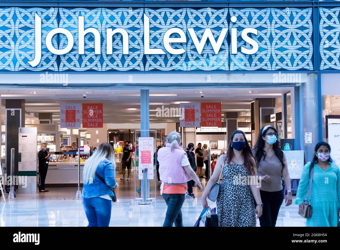 Shoppers exit John Lewis department store at Westfield shopping centre London, England, UK during summer sale Stock Photo