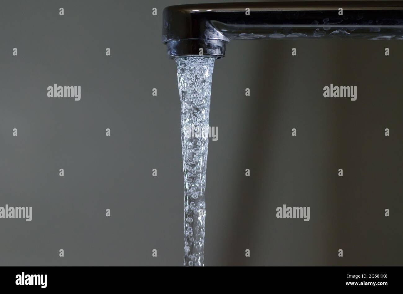 Water with bubbles flows down from the water tap Stock Photo