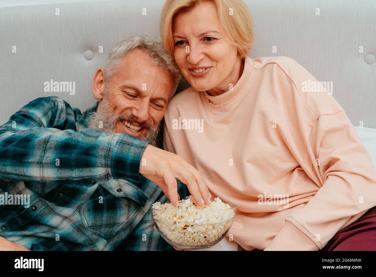 Husband and wife watch a film on the bed and eat popcorn Stock Photo ... photo