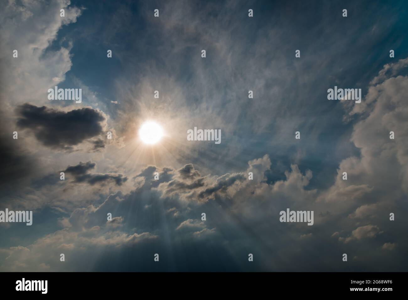 Shining sun with rays in the clouds in the blue sky Stock Photo