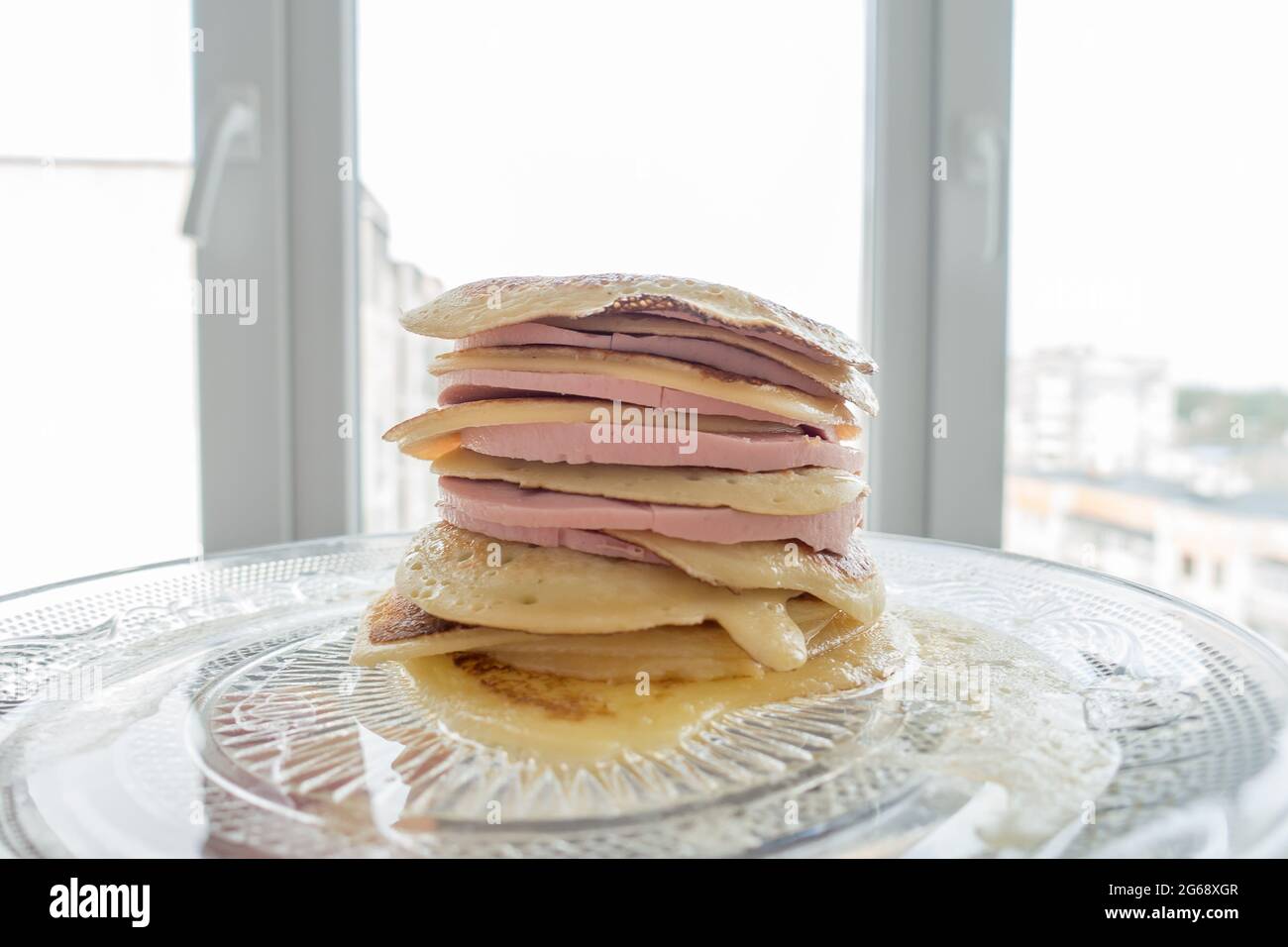 stack of pancakes with a layer of sausage pieces on a plate Stock Photo