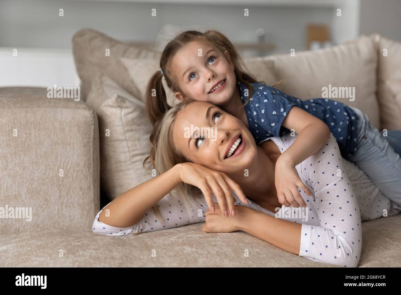 Close up smiling dreamy mother and little daughter looking up Stock Photo
