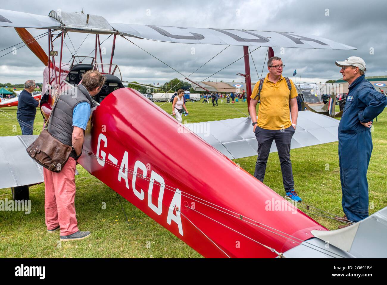 Aviation enthusiast inspect a red 1933 de Havilland Tiger Moth at the Middle Wallop Wheels and Wings airshow in Hampshire, UK Stock Photo
