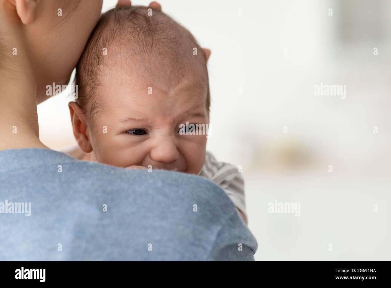 Baby Behavior. Closeup Portrait Of Young Mother Comforting Her Crying Infant Child Stock Photo