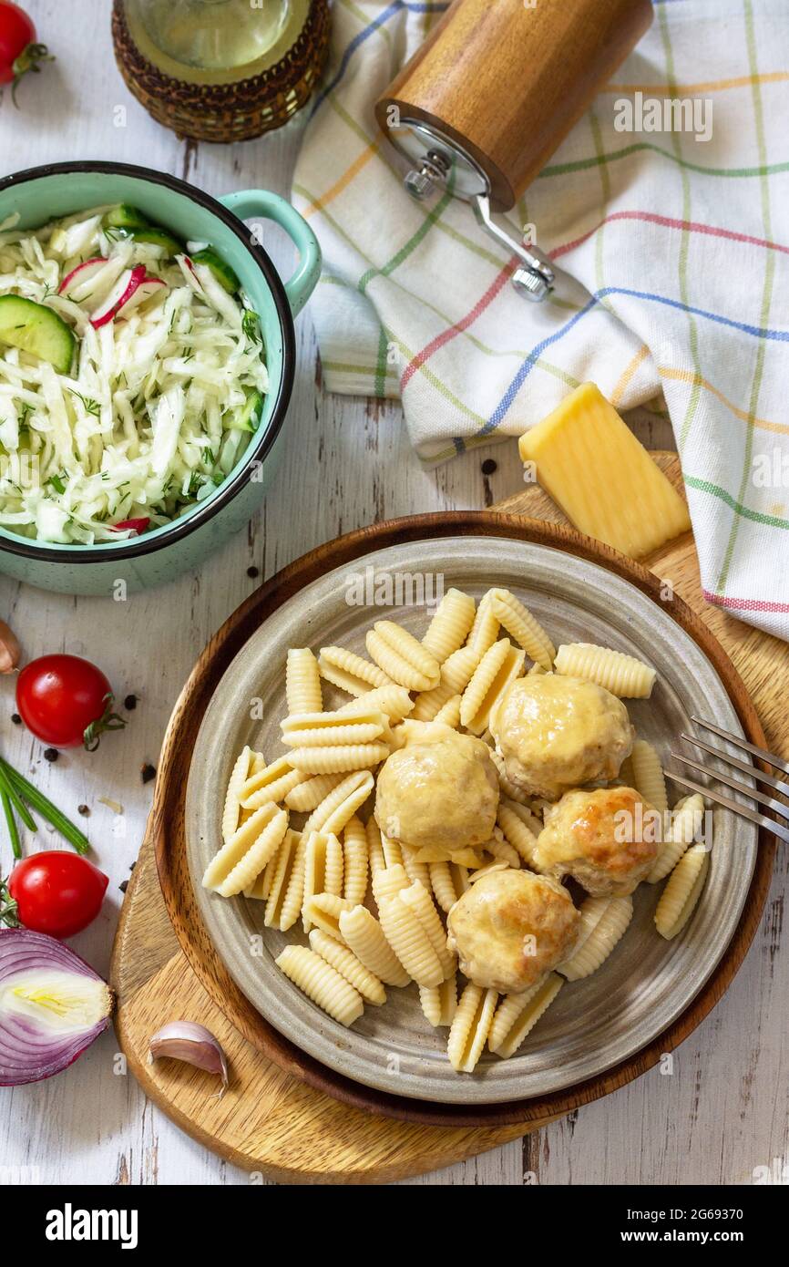 Italian pasta, keto diet lunch. Spaghetti with meatballs in cheese sauce and fresh vegetable salad on a wooden table. Stock Photo