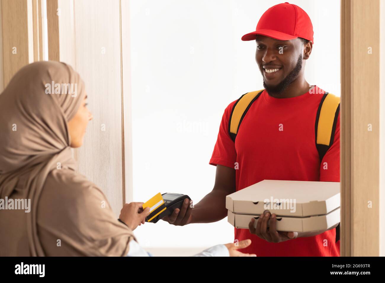 Deliveryman holding POS machine for payment, woman paying with card Stock Photo
