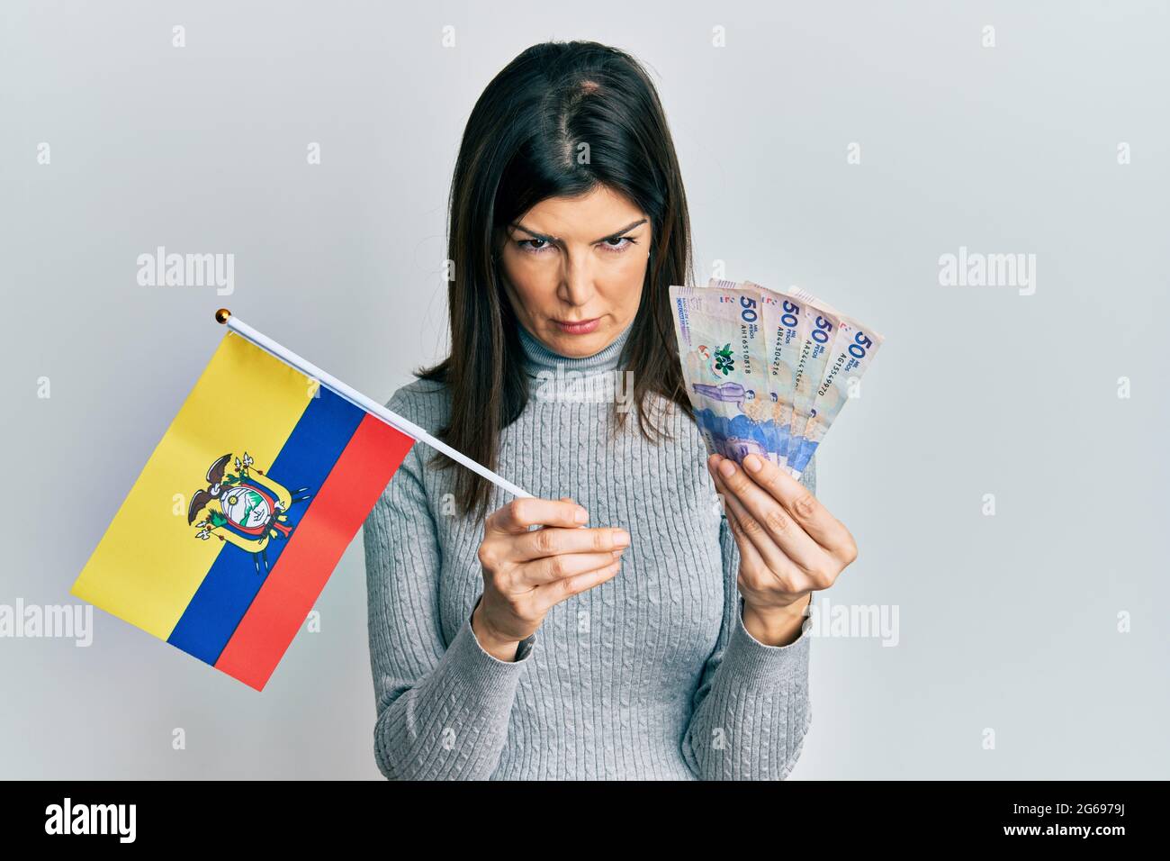 Young hispanic woman holding colombia flag and colombian pesos ...