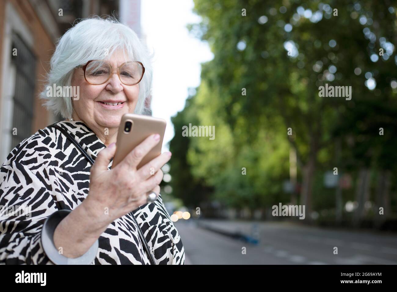 portrait of older woman looking at her cell phone on the street Stock Photo