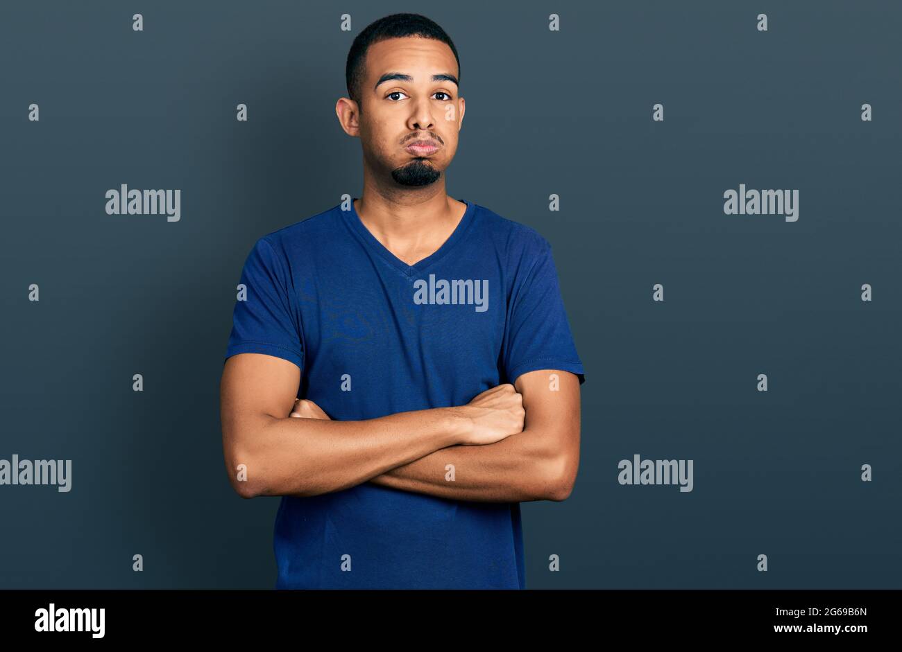 Young african american man with arms crossed gesture puffing cheeks