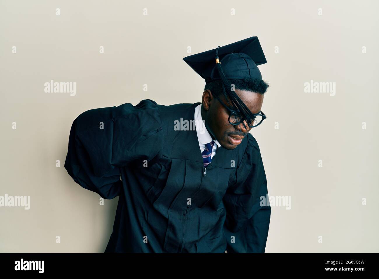 Handsome black man wearing graduation cap and ceremony robe suffering ...