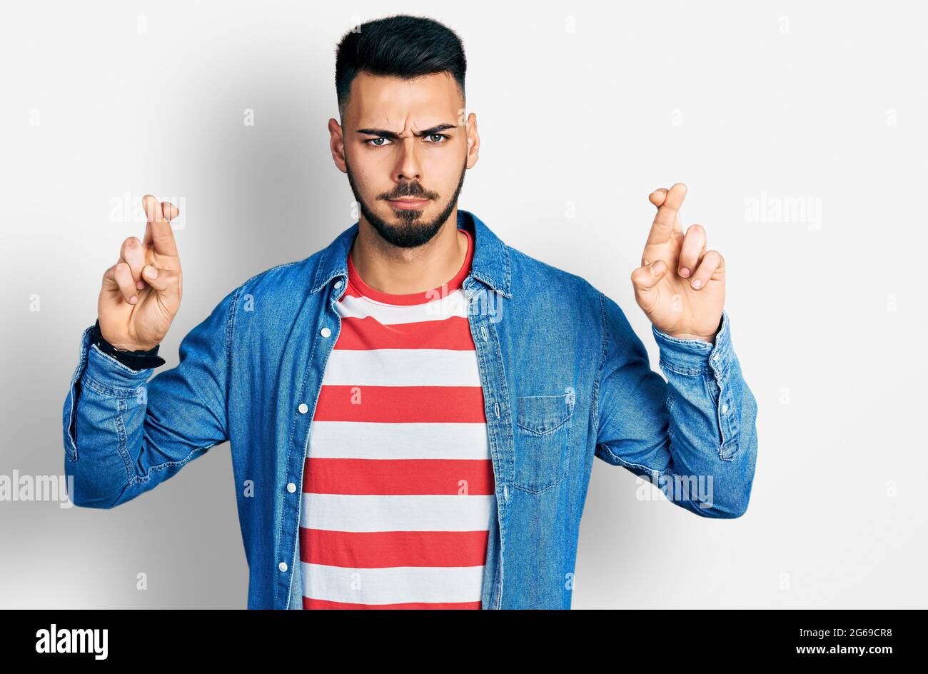 Young hispanic man with beard doing fingers crossed luck gesture ...