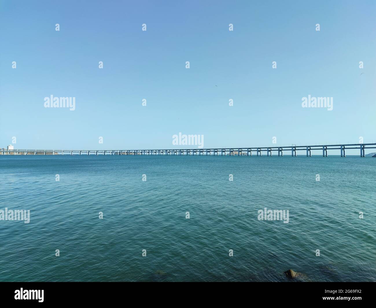 long bridge over the blue sea and the blue sky in sunny day Stock Photo